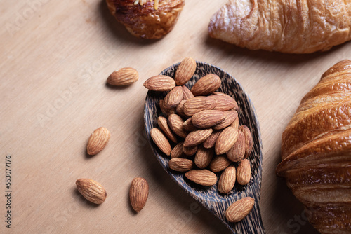 Closeup of almonds in wooden spoon with bread on wooden background, vintage tones, breadbread
 photo