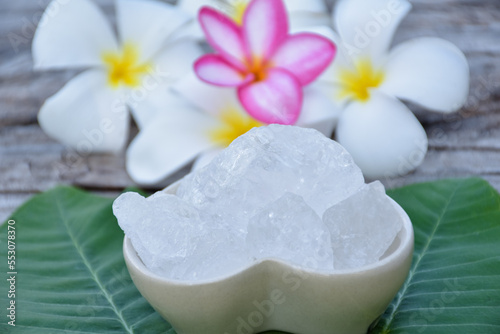 Alum cubes on ceramic pot and plumeria flowers background  concept for herb  bodycare  skincare  waterclear  spa  treatment  disease protection and protect armpit smell. 