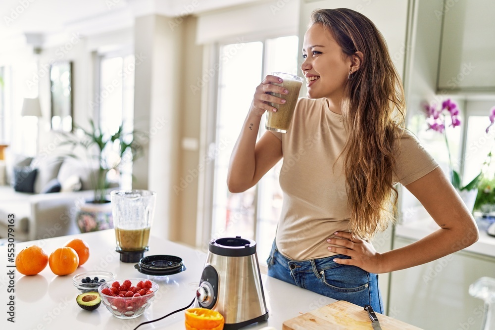 Young beautiful hispanic woman smiling confident holding glass of vegetable smoothie at the kitchen Young beautiful hispanic woman smiling confident holding glass of vegetable smoothie at the kitchen