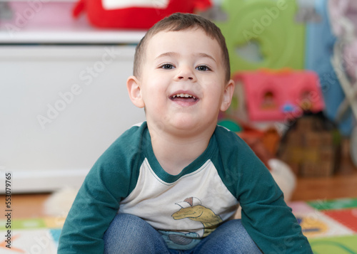 expressive young boy posing for portraits in his room surrounded by toys
