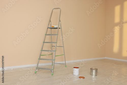 Metal stepladder near pale orange wall indoors. Room renovation