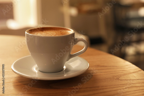 Cup of aromatic hot coffee on wooden table in cafe, closeup. Space for text