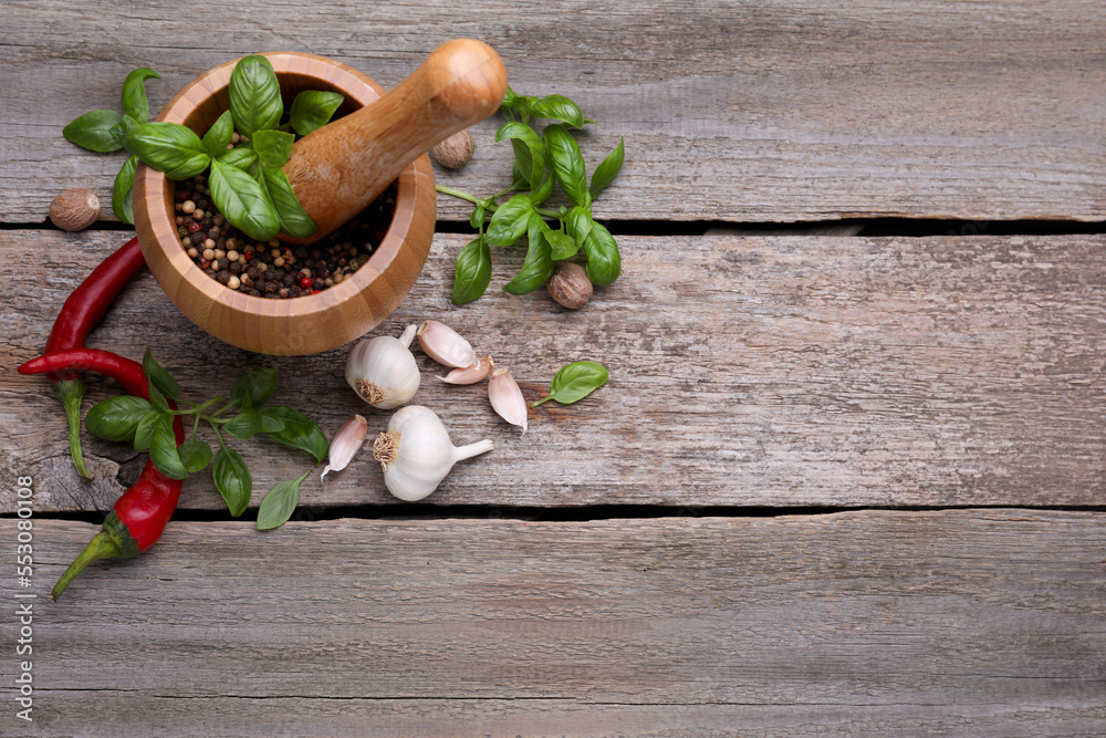 Mortar with pestle and different spices on wooden table, above view. Space for text Mortar with pestle and different spices on wooden table, above view. Space for text