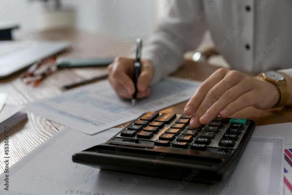 Tax accountant with calculator working at table in office, closeup Tax accountant with calculator working at table in office, closeup