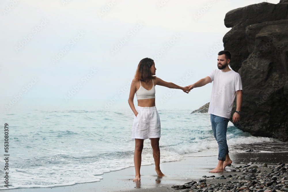 Young couple walking on beach near sea. Space for text Young couple walking on beach near sea. Space for text
