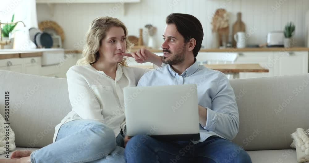 Happy millennial couple spend weekend pastime on internet with laptop, looking at computer screen, do electronic shopping, enjoy e-commerce web site usage, discuss on-line purchase on leisure at home