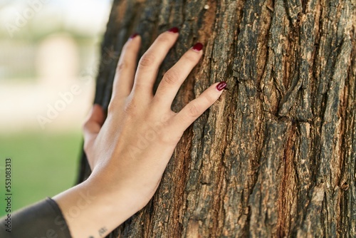 Young beautiful hispanic woman touching tree with hand at park © Krakenimages.com