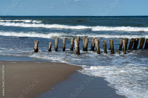 View of the Baltic Sea and wooden breakwaters on the Curonian Spit beach on a sunny summer day, Kaliningrad region, Russia photo