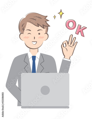 パソコン操作でOKサインを出すスーツ姿の若い男性