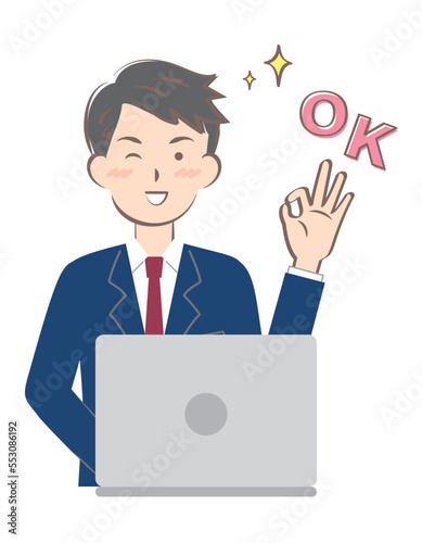 パソコン操作でOKサインを出すスーツ姿の若い男性