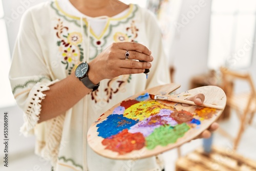 Young hispanic woman mixing color on palette at art studio