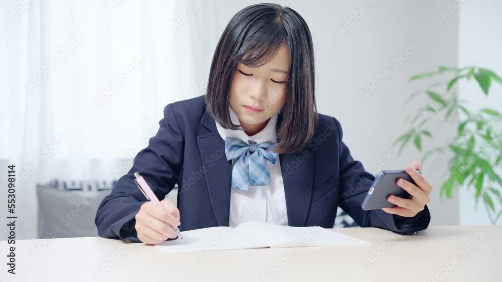 スマホを見ながら勉強する女子学生 オンライン授業 eラーニング スマホを見ながら勉強する女子学生 オンライン授業 eラーニング