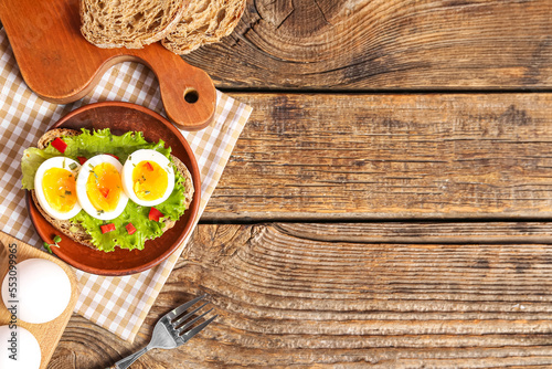 Plate of delicious toast with boiled egg on wooden background