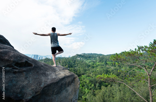 Young man doing yoga on mountain peak
