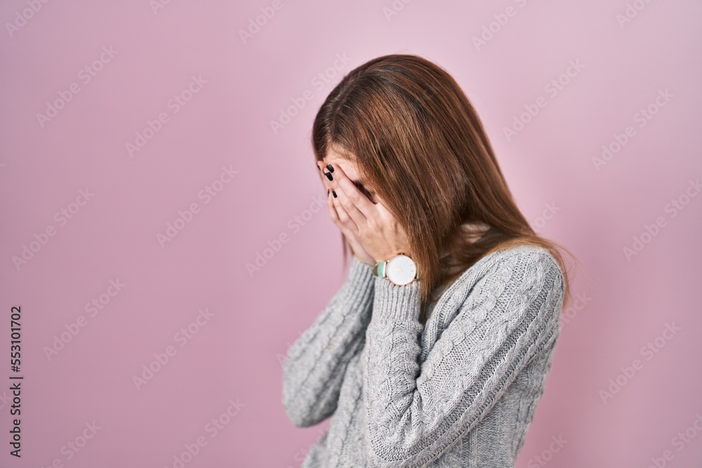 Beautiful woman standing over pink background with sad expression covering face with hands while crying. depression concept. Beautiful woman standing over pink background with sad expression covering face with hands while crying. depression concept.