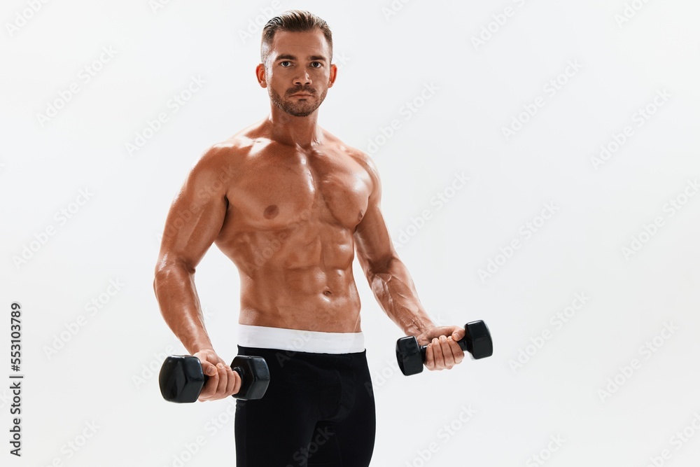 Man athletic body bodybuilder posing with dumbbells with naked torso abs full-length in the background, fitness class. Advertising, sports, active lifestyle, competition, challenge concept. 