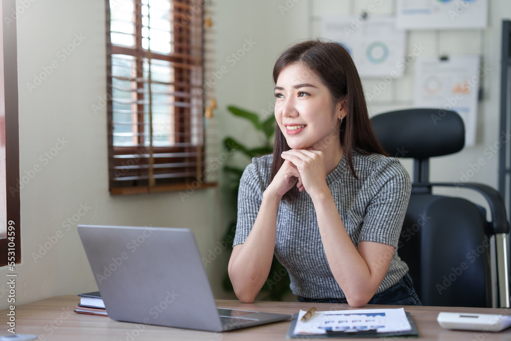 Attractive asian businesswoman sitting at work using laptop and examining many documents in office smiling. Attractive asian businesswoman sitting at work using laptop and examining many documents in office smiling.