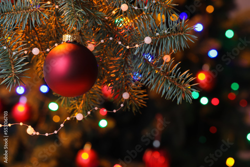 Red Christmas ball on fir tree at night, closeup
