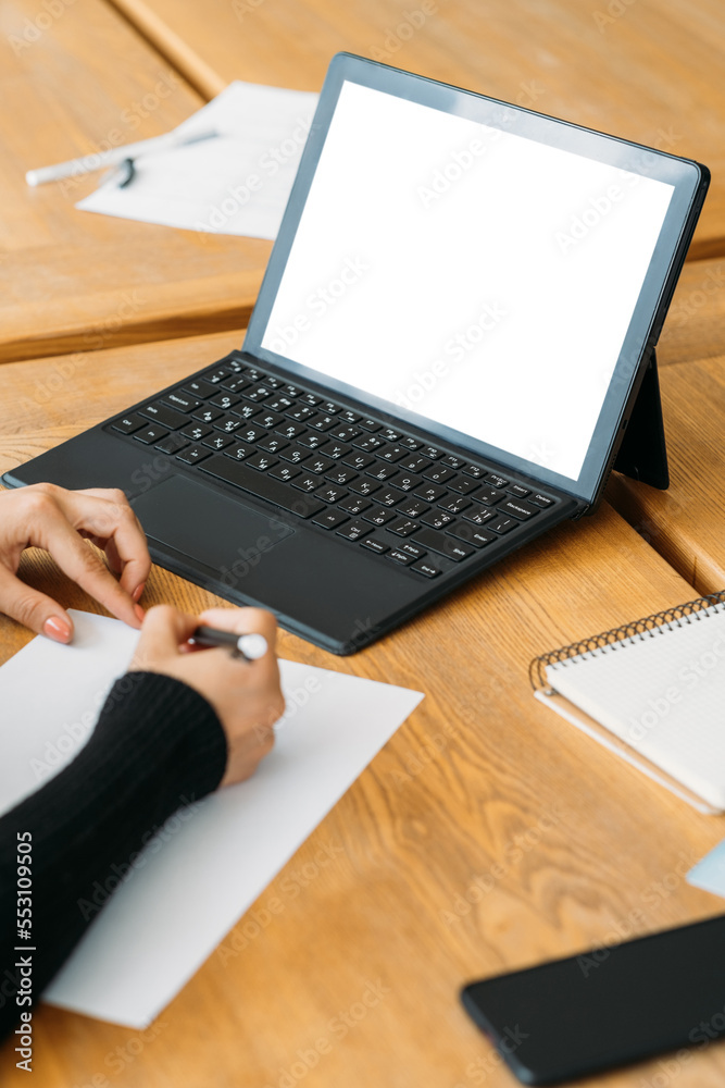 Online education. Digital mockup. Virtual technology. Unrecognizable woman writing paper sitting desk with laptop blank screen in light room interior. Online education. Digital mockup. Virtual technology. Unrecognizable woman writing paper sitting desk with laptop blank screen in light room interior.