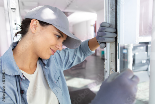 happy woman installing window handle with screwdriver