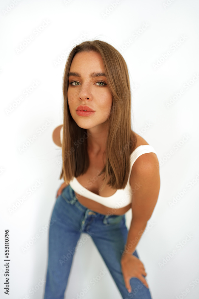 Young model woman in white underwear and jeans posing on studio background Young model woman in white underwear and jeans posing on studio background