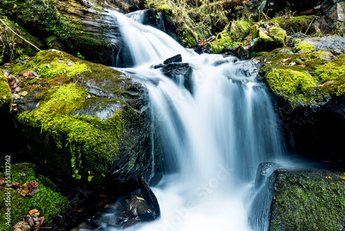 Blurred waterfall throughing mossy rocks