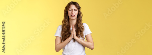 Please beg you. Sobbing timid insecure distressed cute whining girl crying upset close eyes grimacing hold hands pray pleading asking favour apologizing sincere hope for pity yellow background photo