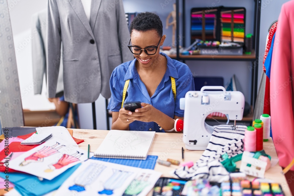 African american woman tailor smiling confident using smartphone at tailor shop