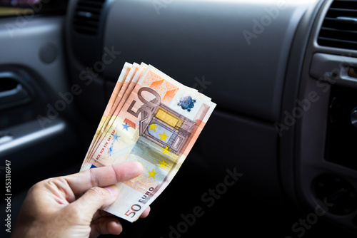 A male businessman pays taxi fare in euros with a tip for excellent service. Business concept.