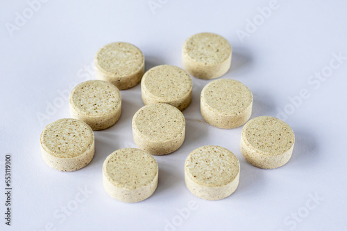 Round puck tablets of irregular beige color on a white background. Supplements DGL liquorice root. sustainability 