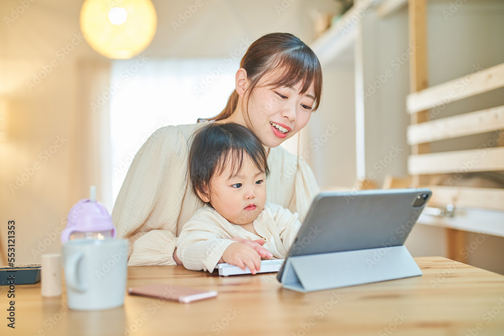 赤ちゃんを抱えてパソコンを操作する女性 赤ちゃんを抱えてパソコンを操作する女性