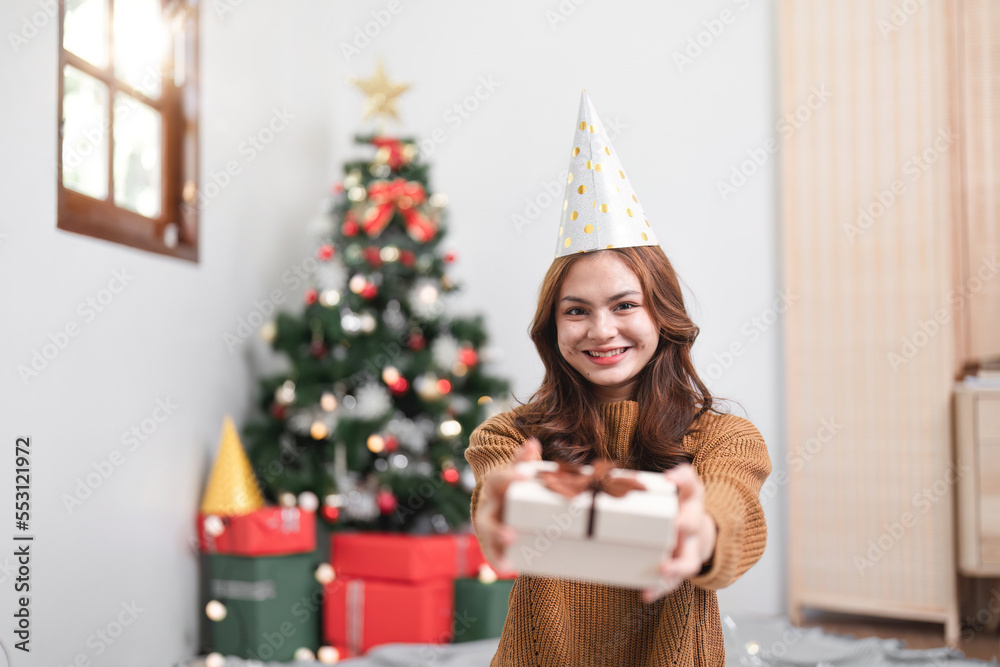 Portrait smiling girl hold gift box sit on floor in house indoors with x-mas christmas decoration