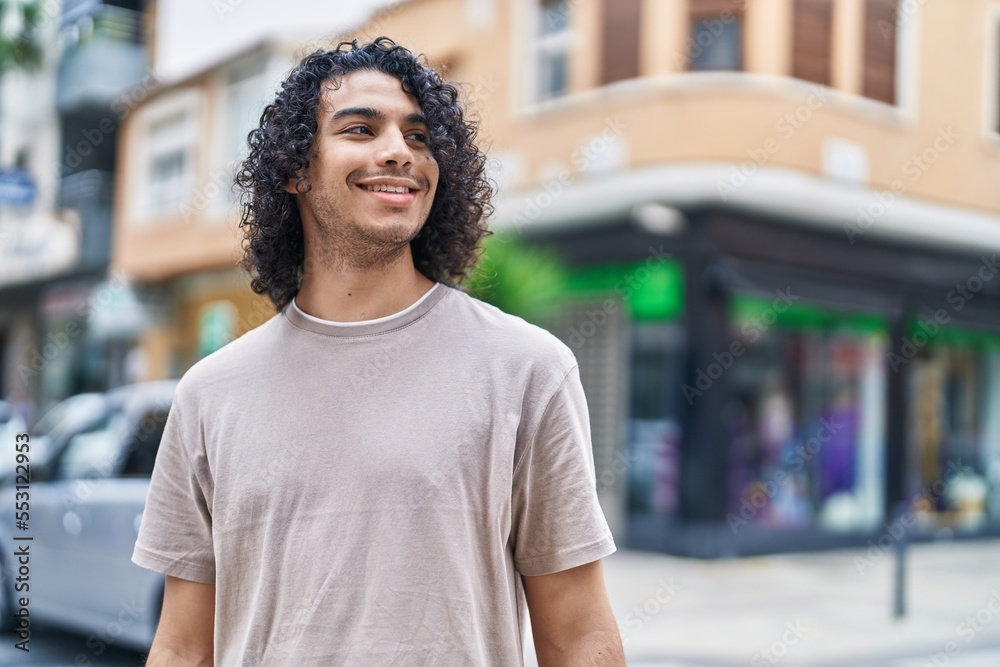 Young latin man smiling confident looking to the side at street Young latin man smiling confident looking to the side at street