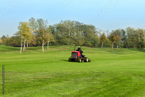 Worker moving grass on golf course