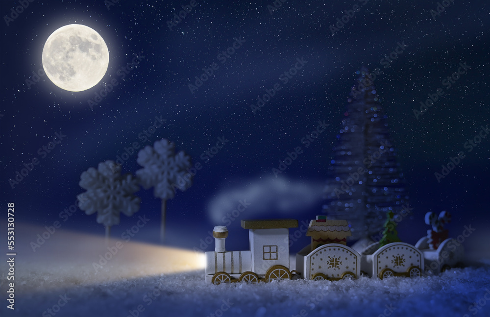 Fototapeta premium New Year's background, a holiday card with a wooden train in the snow. christmas tree. Starry night.