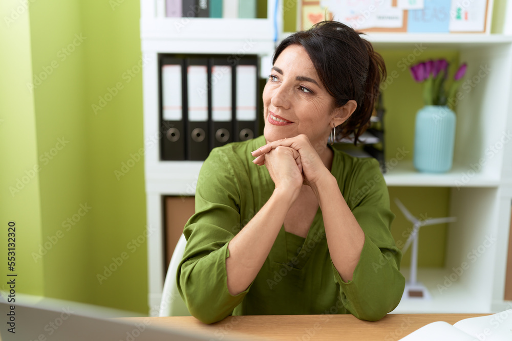 Middle age hispanic woman business worker smiling confident sitting on table at office Middle age hispanic woman business worker smiling confident sitting on table at office