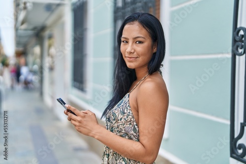 Young beautiful latin woman smiling confident using smartphone at street