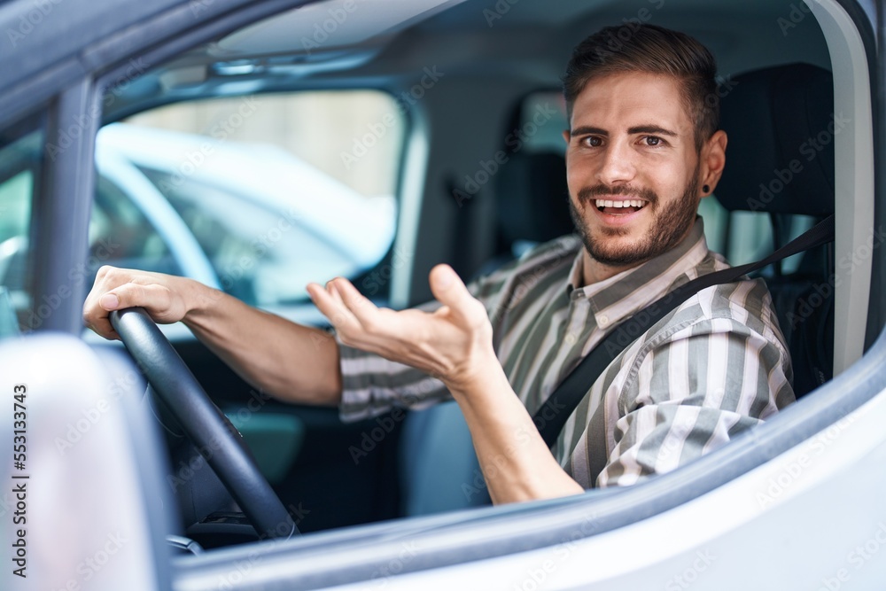 Hispanic man with beard driving car celebrating achievement with happy smile and winner expression with raised hand