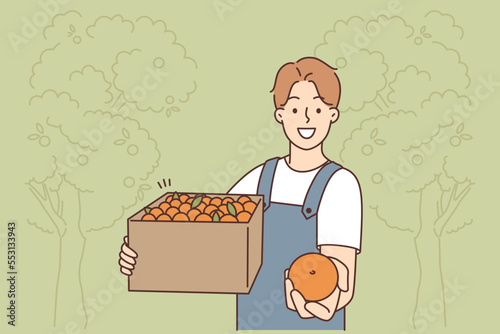 Smiling male farmer with box of fruits 