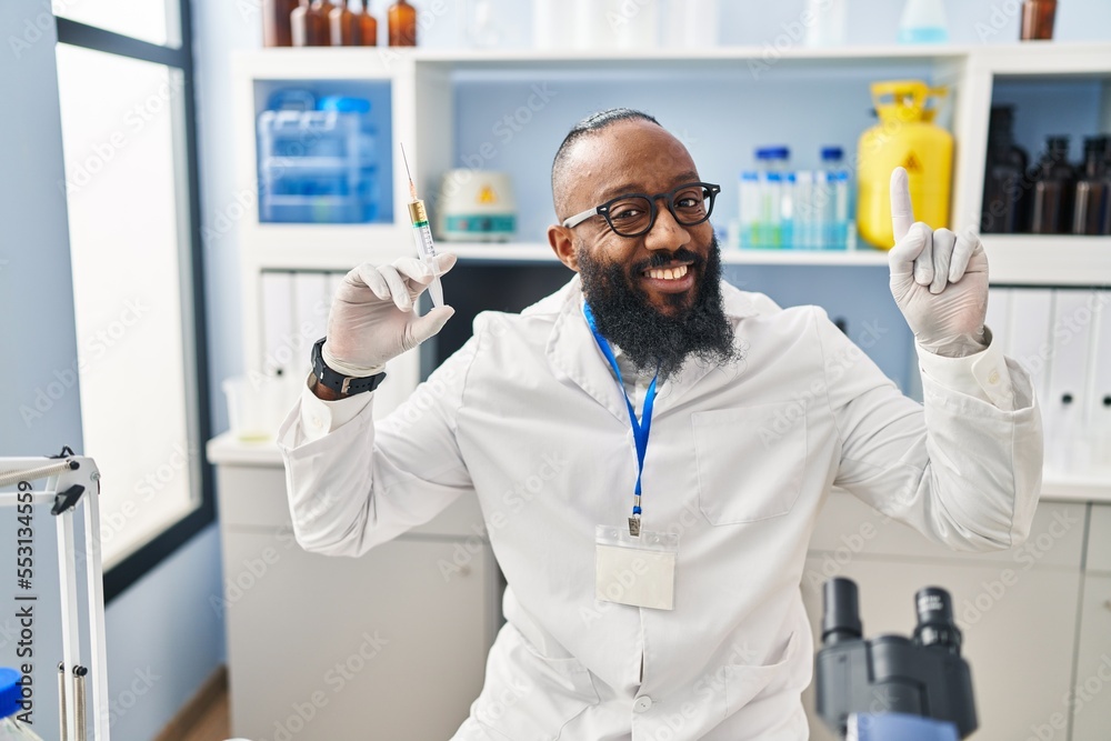 African american man working at scientist laboratory holding syringe surprised with an idea or question pointing finger with happy face, number one African american man working at scientist laboratory holding syringe surprised with an idea or question pointing finger with happy face, number one