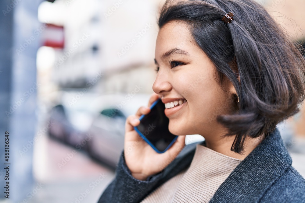 Young woman smiling confident talking on the smartphone at street