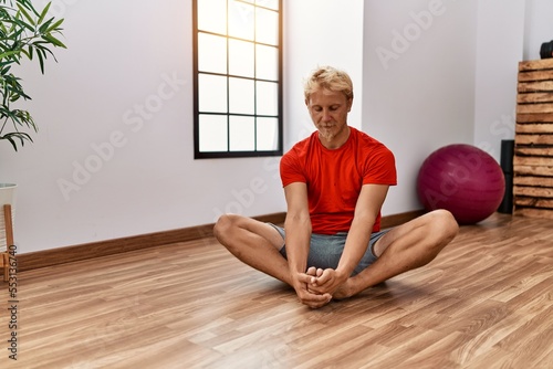 Young caucasian man stretching at sport center