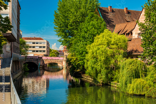 Germany, Bavaria, Nuremberg,Green trees along Pegnitz river in summer with Museum Bridge in background photo