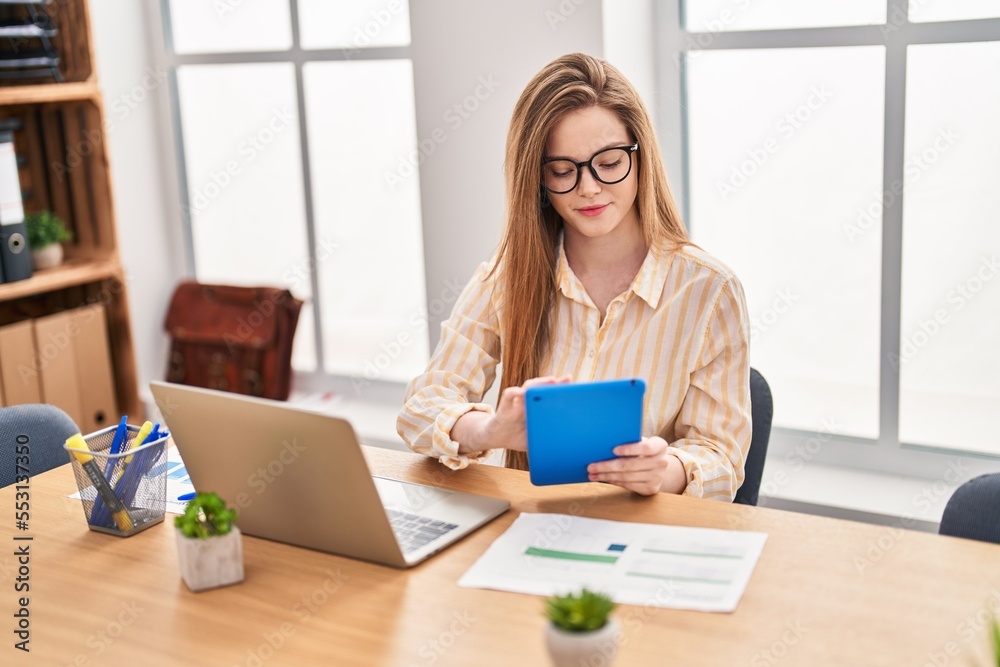 Young blonde woman business worker using laptop and touchpad working at office Young blonde woman business worker using laptop and touchpad working at office