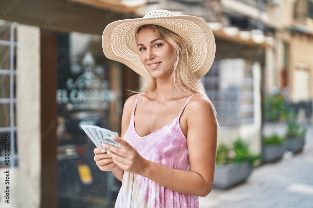 Young blonde woman tourist smiling confident counting dollars at coffee shop terrace