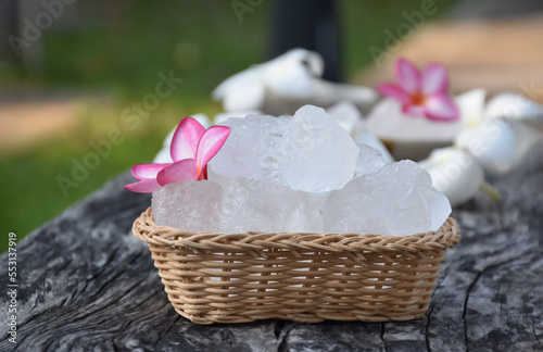 Soft focus of Alum cubes and plumeria flower on wicker basket, blurred background, concept for herb, bodycare, skincare, waterclear, spa, treatment, disease protection and protect armpit smell. photo