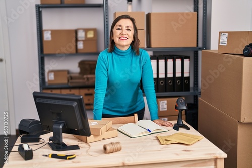 Middle age woman ecommerce business worker standing at office