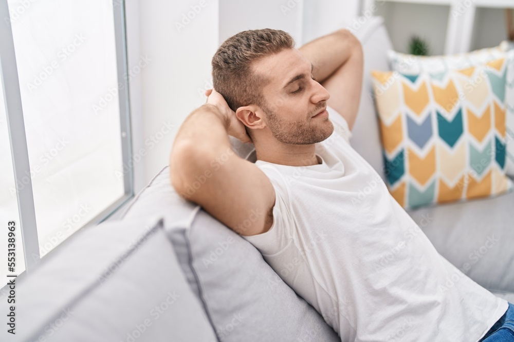 Young caucasian man relaxed with hands on head sitting on sofa at home Young caucasian man relaxed with hands on head sitting on sofa at home