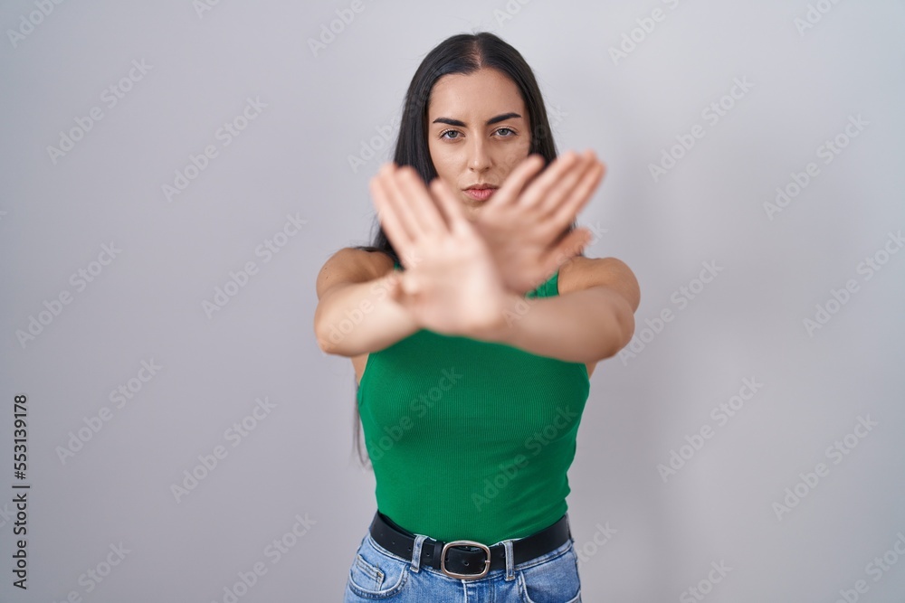 Young woman standing over isolated background rejection expression crossing arms and palms doing negative sign, angry face Young woman standing over isolated background rejection expression crossing arms and palms doing negative sign, angry face