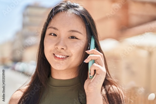 Young chinese woman smiling confident talking on the smartphone at street
